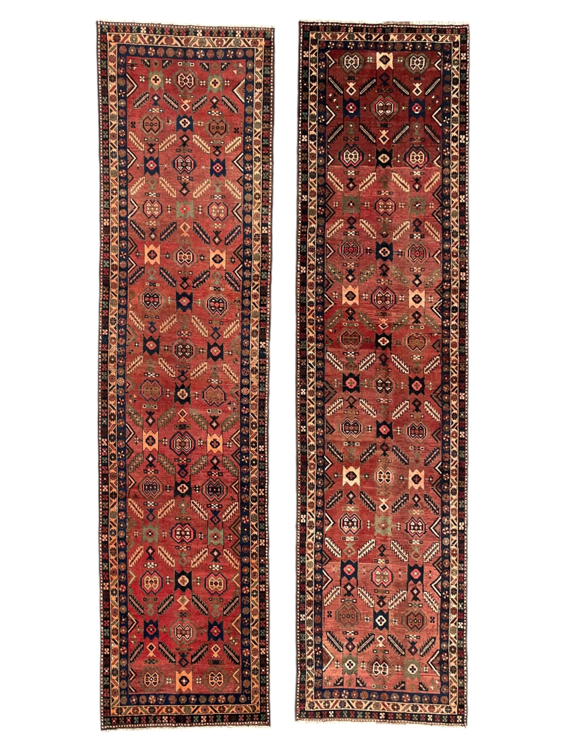 Near pair of Persian Azerbaijan red ground runners, each rug decorated with Nazarlik and stylised leaf motifs, enclosed with three band border decorated with flower heads and geometric motifs 

406cm x 99cm 
409cm x 102cm
