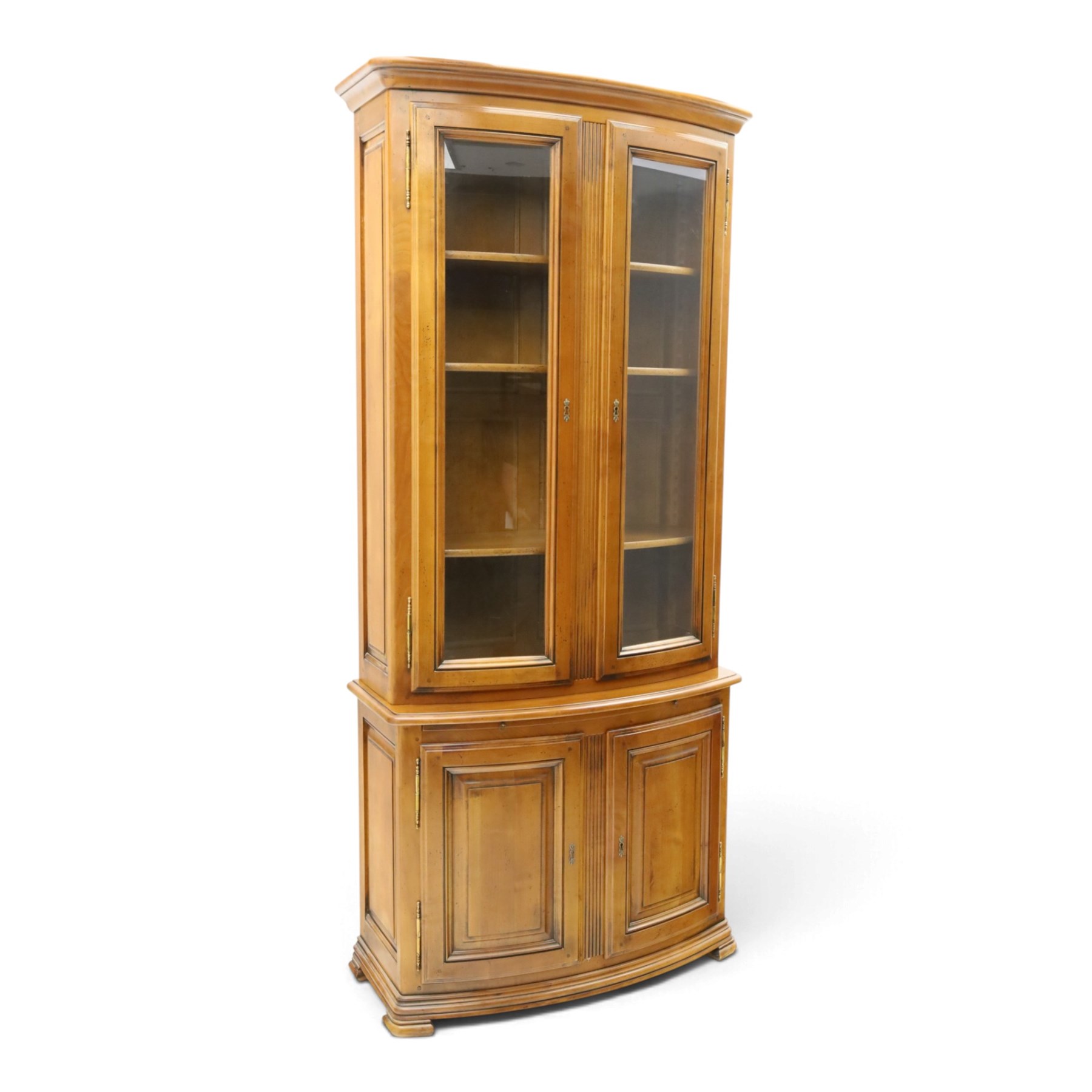 Wesley Barrell - French cherry wood bow front display cabinet, the upper section with glazed doors and three adjustable shelves, raised on cupboard base with brushing slide and further adjustable shelf, raised on a moulded plinth base with bracket feet