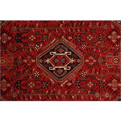 Persian tribal hand-knotted rug, crimson ground, madder field with central stepped lozenge medallion with scattered floral and geometric spandrels with rosette border 