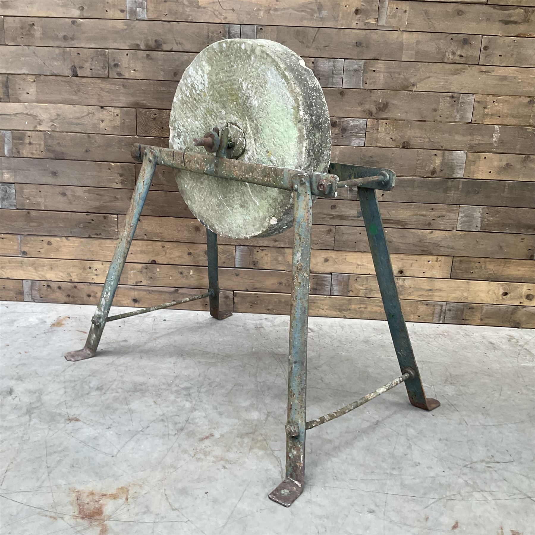 Vintage grindstone sharpening wheel mounted on metal stand, and a cast iron water pump