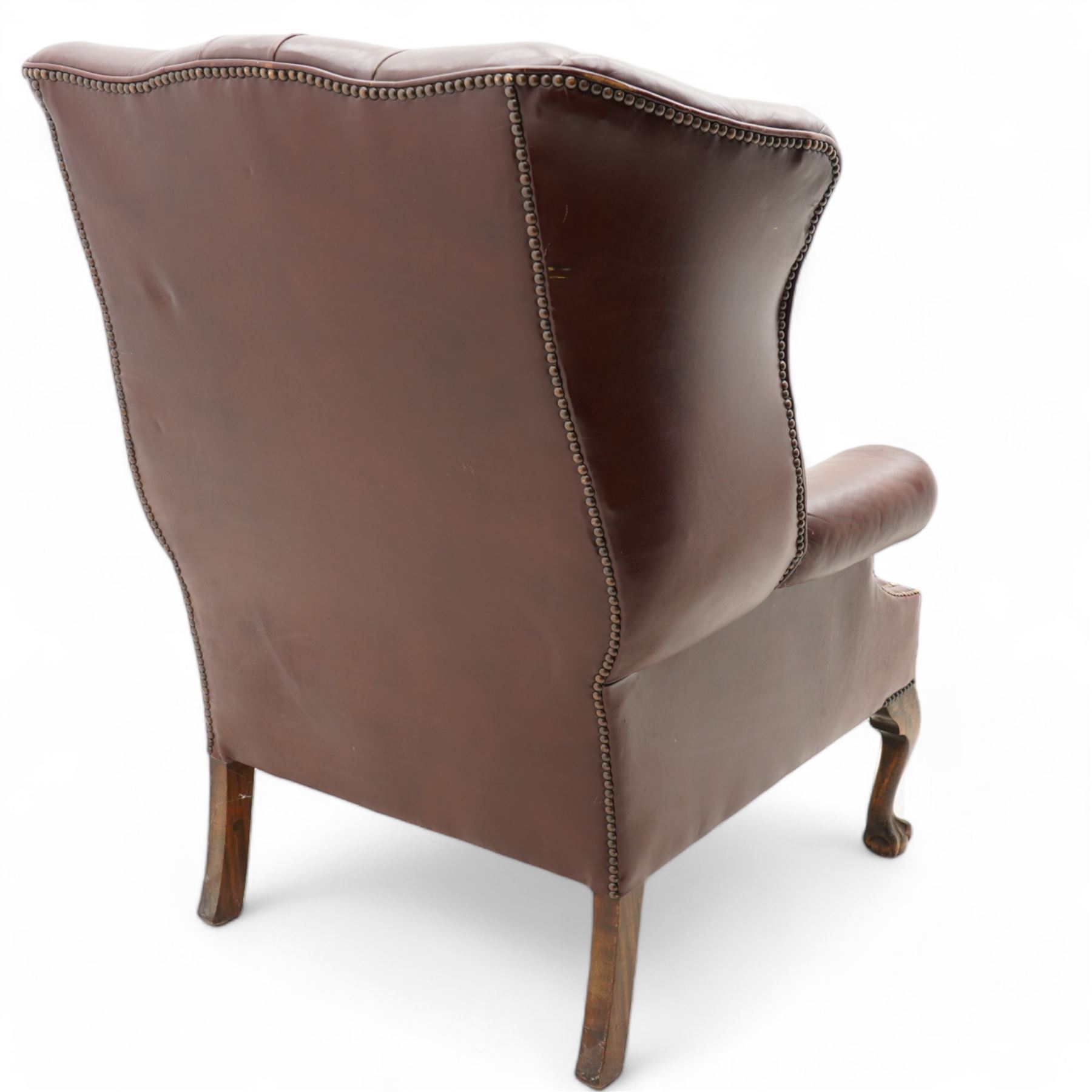Georgian design leather wingback armchair, deep-buttoned burgundy leather upholstery with rolled arms, studded detail along the edges, raised on cabriole supports terminating in claw and ball feet
