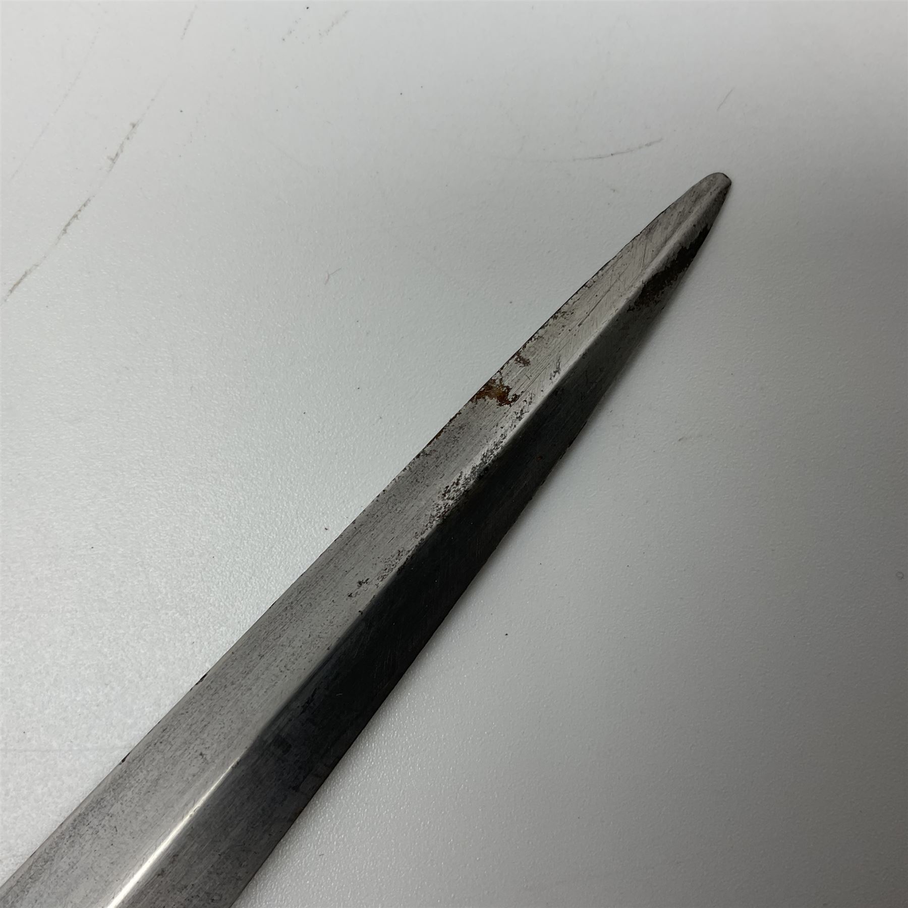 First Pattern Fairburn Sykes ''F-S'' Fighting Knife by Wilkinson Sword Ltd., the 17cm double edge steel blade with raised medial ridge to each side, each side of the ricasso with a recessed panel, one side with maker's name, the opposing side etched THE F~S FIGHTING KNIFE, with nickel plated brass recurving crossguard and diamond cut grip; in leather scabbard with metal chape