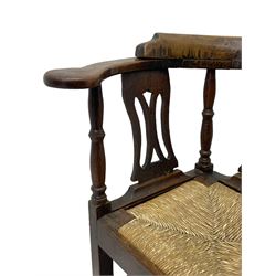 18th century country elm and oak corner chair, the shaped cresting rail terminating to swept arm resets, supported by turned columns and pierced shaped splats, over a drop-in rush seat, raised on square supports united by box stretcher