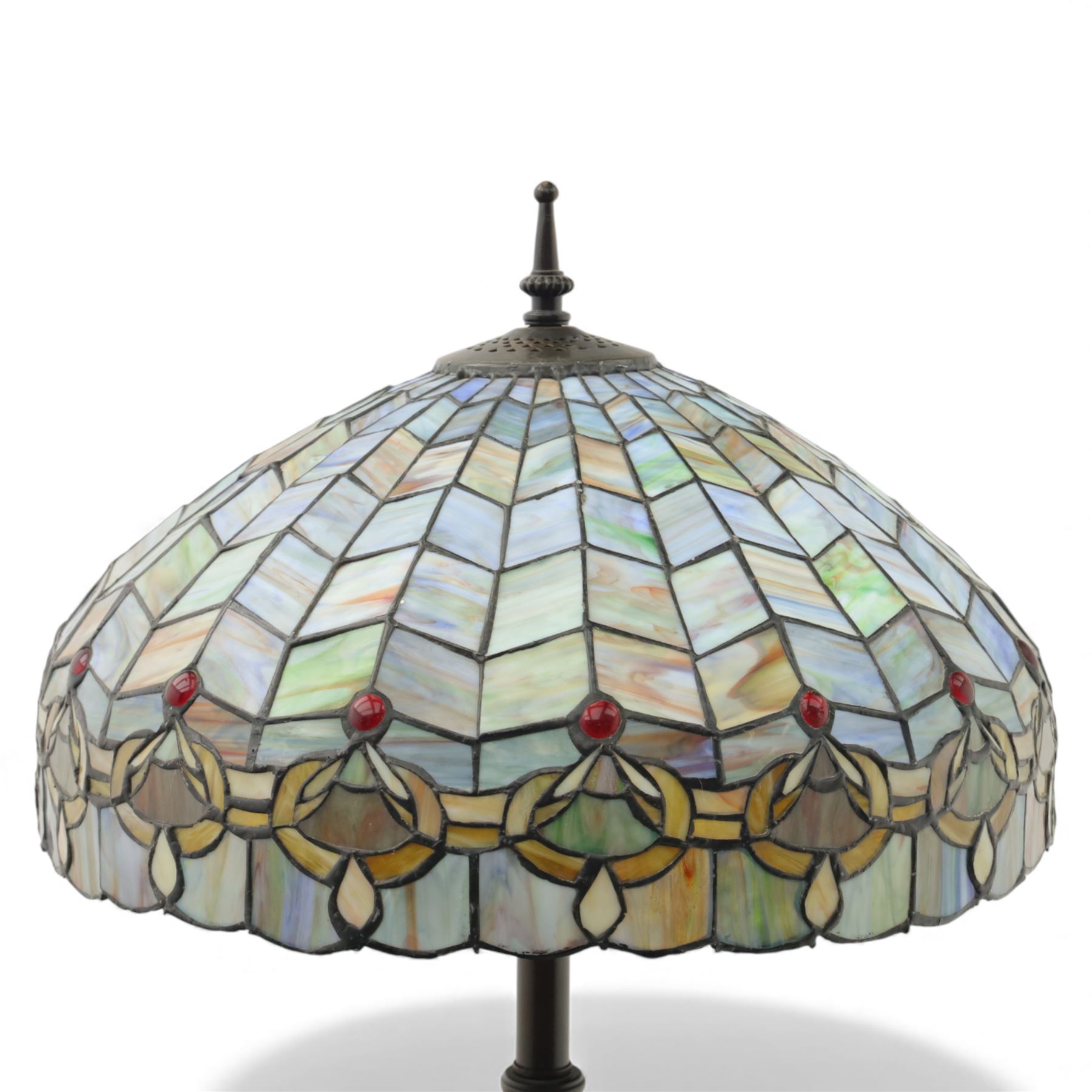 Late 20th century Tiffany style standard lamp, the leaded glass domed shade composed of geometric panels in mottled pastel tones, bordered by stylised foliate motifs and coloured cabochons, raised on a spiral twist metal column and circular moulded base