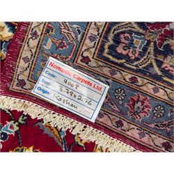 Northeastern Persian Meshed hand-knotted carpet, madder red field with an all-over design of scrolling vines, palmettes, and rosettes, within a dark blue border of palmettes and arabesques 