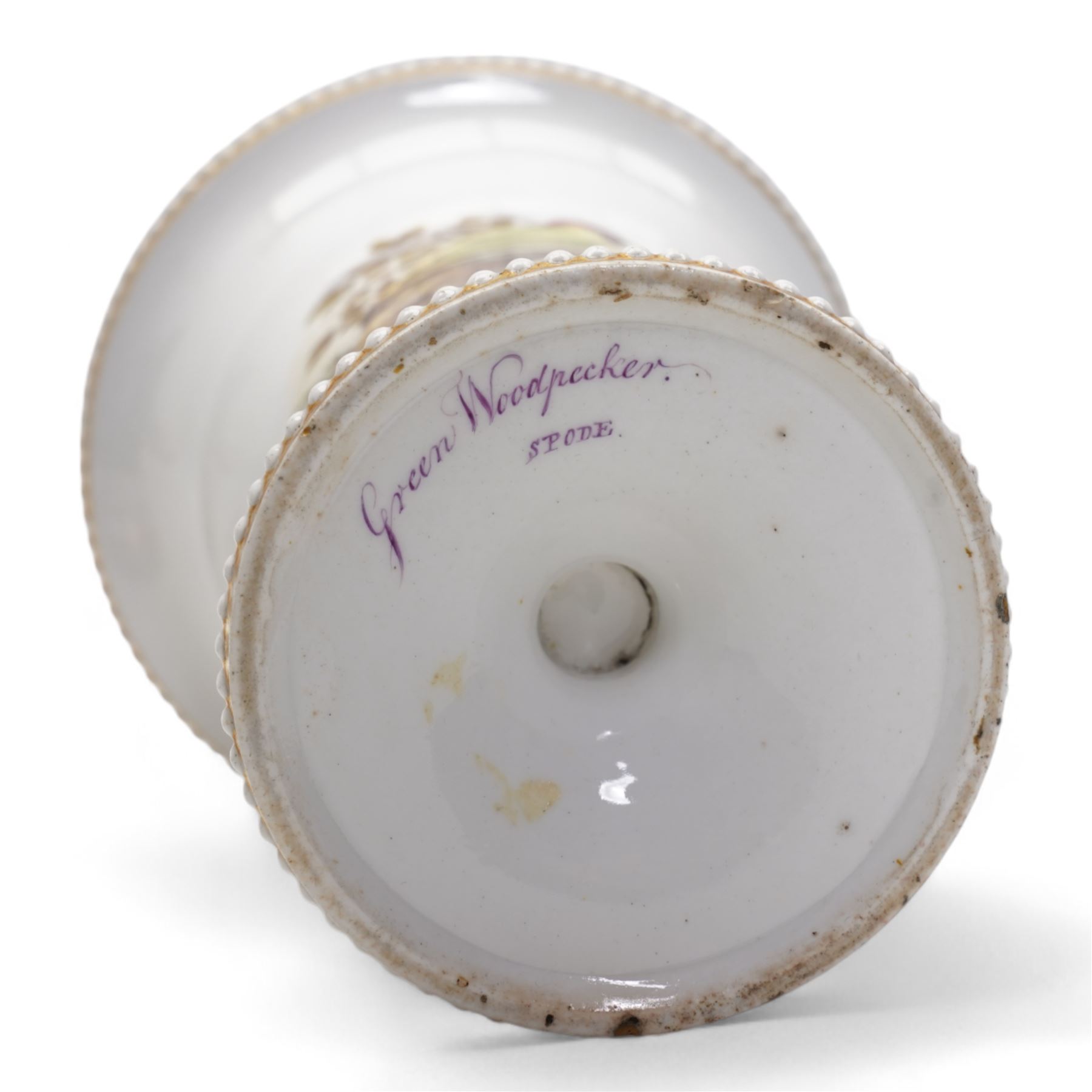 Early 19th century Spode spill vase, of cylindrical form with flared rim, hand painted with a Green Woodpecker perched on a branch, within beaded borders, titled beneath, H16cm, together with a Spode chocolate cup turnover rim stand, decorated in the imari pattern, no. 2630, painted marks beneath, D14cm (2)