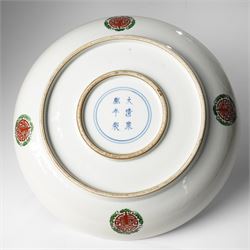 Chinese charger, decorated in blue, green and red enamels with a four clawed dragon chasing the flaming pearl amidst waves and flower heads, the rim with border of alternating reserves of auspicious emblems and flower scrolls, bearing apocryphal Kangxi mark beneath, D38cm 

