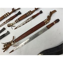 Indian kukri with 29cm curving steel blade and nickel mounted horn grip; in leather covered scabbard with one skinning knife L42cm overall; Hitler Youth knife with scabbard in relic condition; and three African graduated knives each with crudely carved wooden grips and painted leather covered scabbards (5)