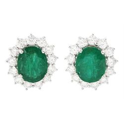 Pair of 18ct white gold emerald and diamond cluster earrings, each stud set with a single ...