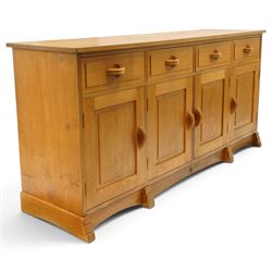 Acorn Industries - oak dresser base or sideboard, the rectangular top over three drawers with protruding oak handles, over four panelled cupboard doors enclosing a single shelf, raised on stepped feet, carved with acorn signature, by Alan Grainger, Brandsby