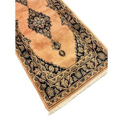 Persian pale peach ground rug, the field decorated with two floral design indigo ground medallions, the border with trailing foliage interspersed with stylised plat motifs, within guard stripes 