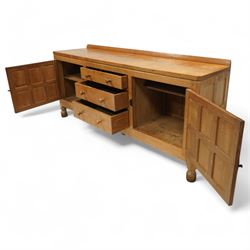 Mouseman - oak sideboard rectangular adzed top with raised back over three central drawers and two flanking cupboards, enclosed by panelled doors with wrought metal fixtures, the canted upright carved with mouse signature, on octagonal feet, by the workshop of Robert Thompson, Kilburn