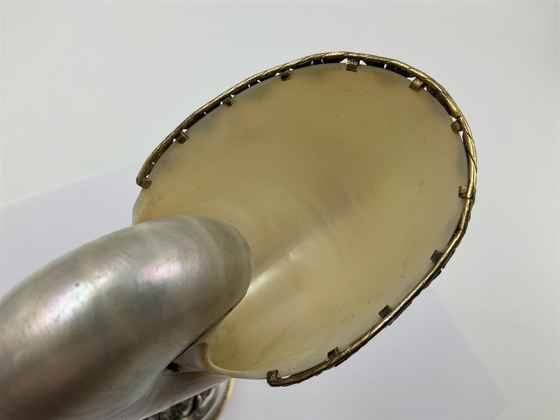 Modern limited edition silver mounted nautilus shell cup, no. 42/150, the pearlescent shell cup with silver-gilt strapwork to rim, upon a stem modelled as a putto supporting a gilt cornucopia and circular domed foot depicting Poseidon amongst swirling waves, hallmarked by St James House Company, London 1980,  H17.5cm