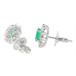 Pair of 18ct white gold emerald and diamond cluster earrings, each stud set with a single oval cut emerald surrounded by round brilliant cut diamonds, stamped, total emerald weight approx 0.90 carat, total diamond weight approx 0.60 carat