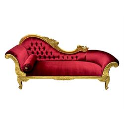 Victorian design giltwood chaise longue, the curved backrest and seat upholstered in deep red velvet with tufted detailing, the frame carved with floral motifs and scrolling acanthus leaves, raised on shaped cabriole supports