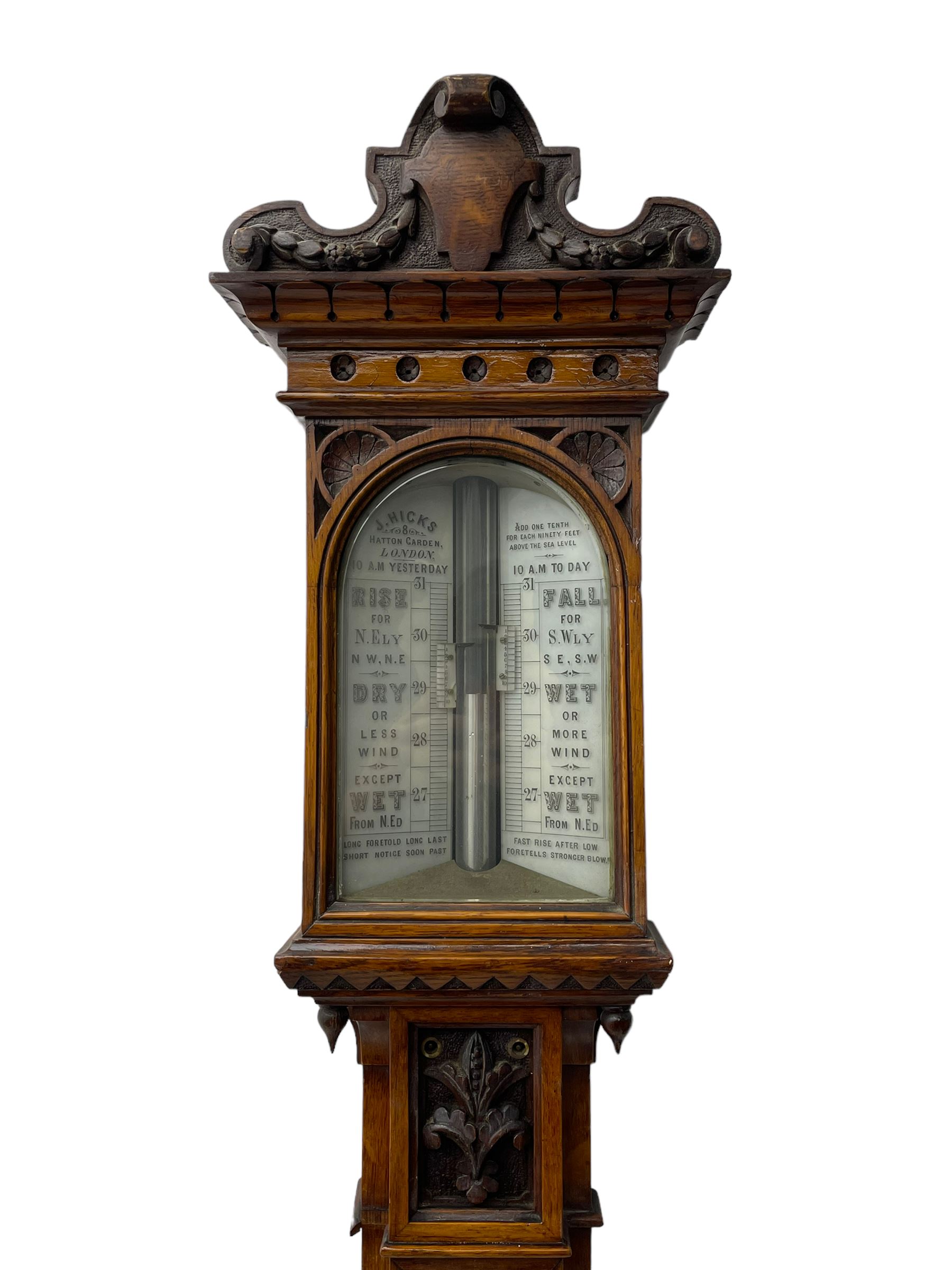 J Hicks - Hatton Garden London, - late 19th century carved oak cased Fitzroy barometer in a richly carved case with a carved crested pediment and square cistern cover, inverted opaline register reflecting FitzRoy's predictions and a scale from 27 to 31 inches of barometric pressure, with a thick bore cistern tube and adjustable rack and pinion twin vernier, fitted with a glazed snail bulb mercury thermometer recording the air temperature in both Fahrenheit and Celsius. Mercury clean and present.
James Joseph Hicks was born in Ireland, however, early in his life he moved to London where he was apprenticed to the instrument maker Louis P Casella. In 1860 he went into business in his own right as a scientific instrument maker at 8 Hatton Gardens. In 1864 he was granted membership to the British Meteorological Society and exhibited instruments at the Royal Society Exhibitions between 1876 and 1913. Hicks was one of London's most prolific and eminent barometer makers. 