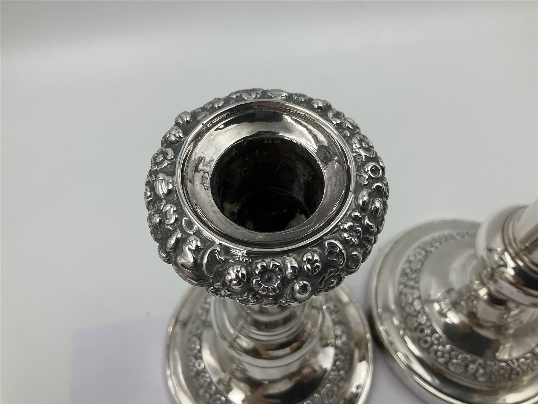 Four George III silver candlesticks, each upon knopped stem and weighted circular stepped foot, the foot and removable sconce repousse decorated with a band of flower heads, hallmarked to sconce and foot Thomas & John Settle, Sheffield 1820, H17.5cm