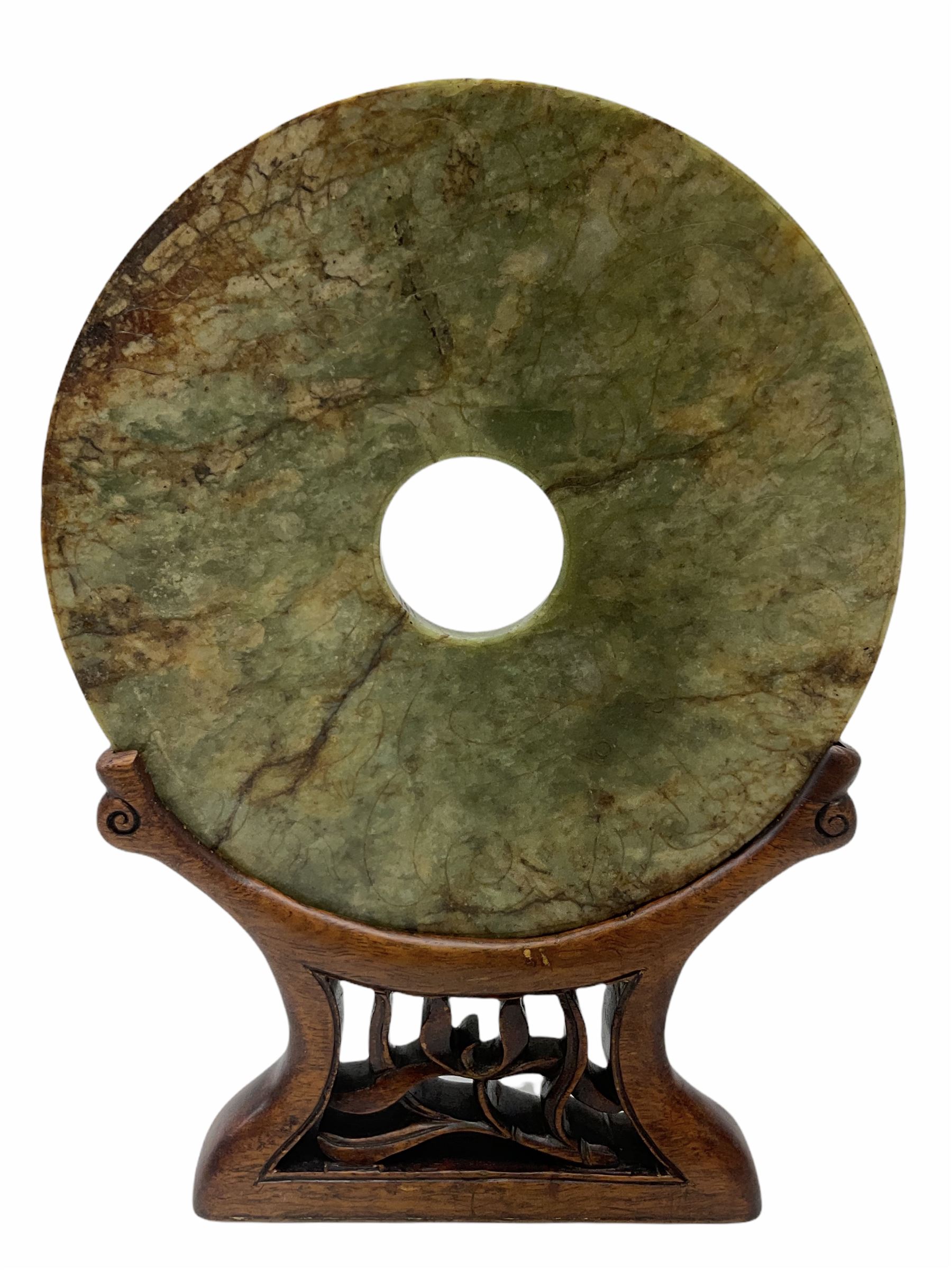 Large Chinese green and russet jade Bi-Disc, engraved with Taotie masks and tigers in the style of the Western Han dynasty, upon carved hardwood stand, disk D21cm
