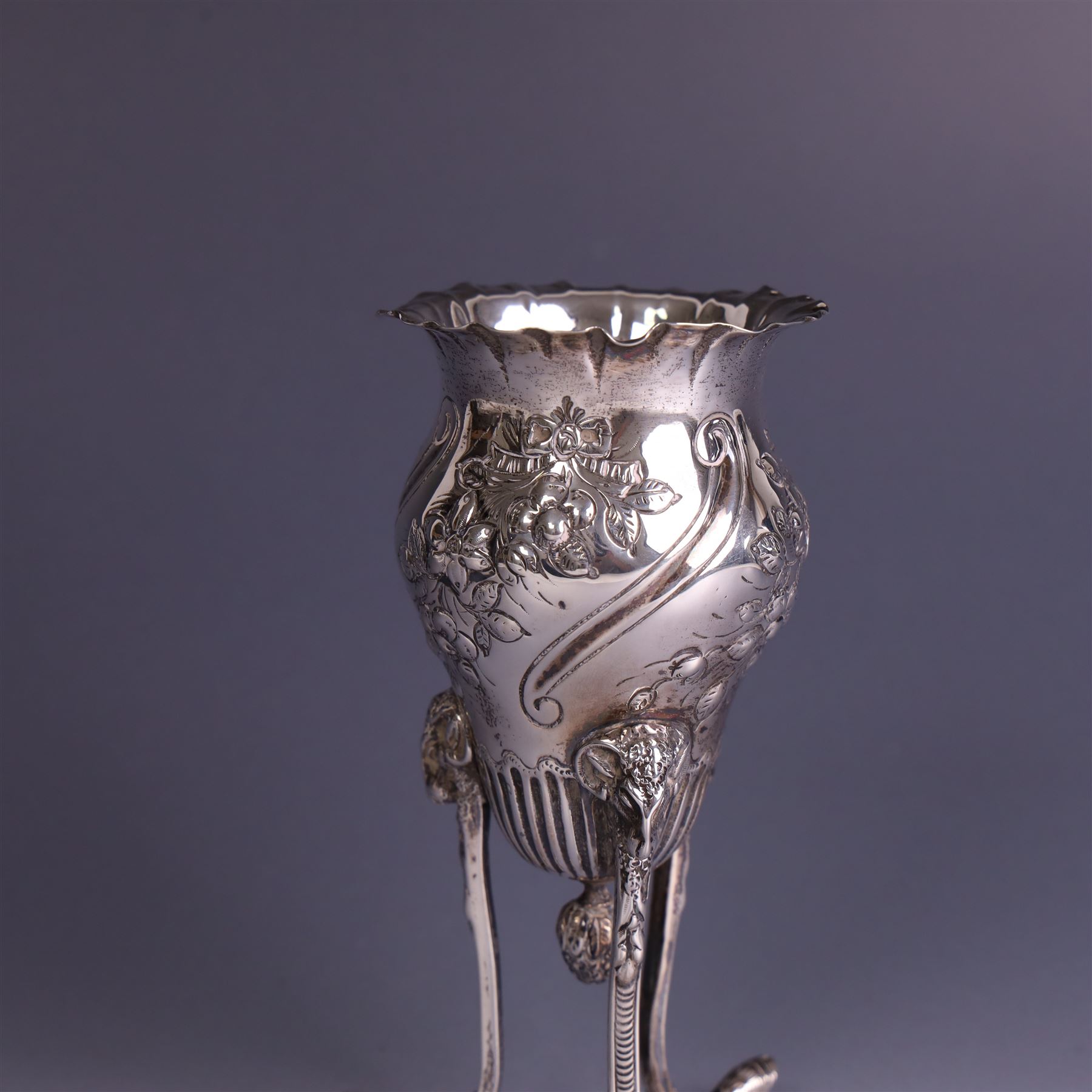 Late Victorian silver vase, of baluster form with fluted rim, the body with embossed floral decoration, upon three tall legs with ramshead mounts, hallmarked William Comyns & Sons, London 1890, H13.5cm