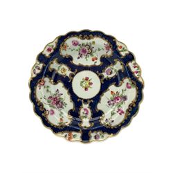 18th century Worcester tea caddy, of oval form and painted in the Kakiemon palette with reserves of flowers against a blue scale ground, H14cm together with a similar Worcester circular dish, painted with floral sprays, within a scalloped edge, blue crescent mark beneath, D19cm (2)