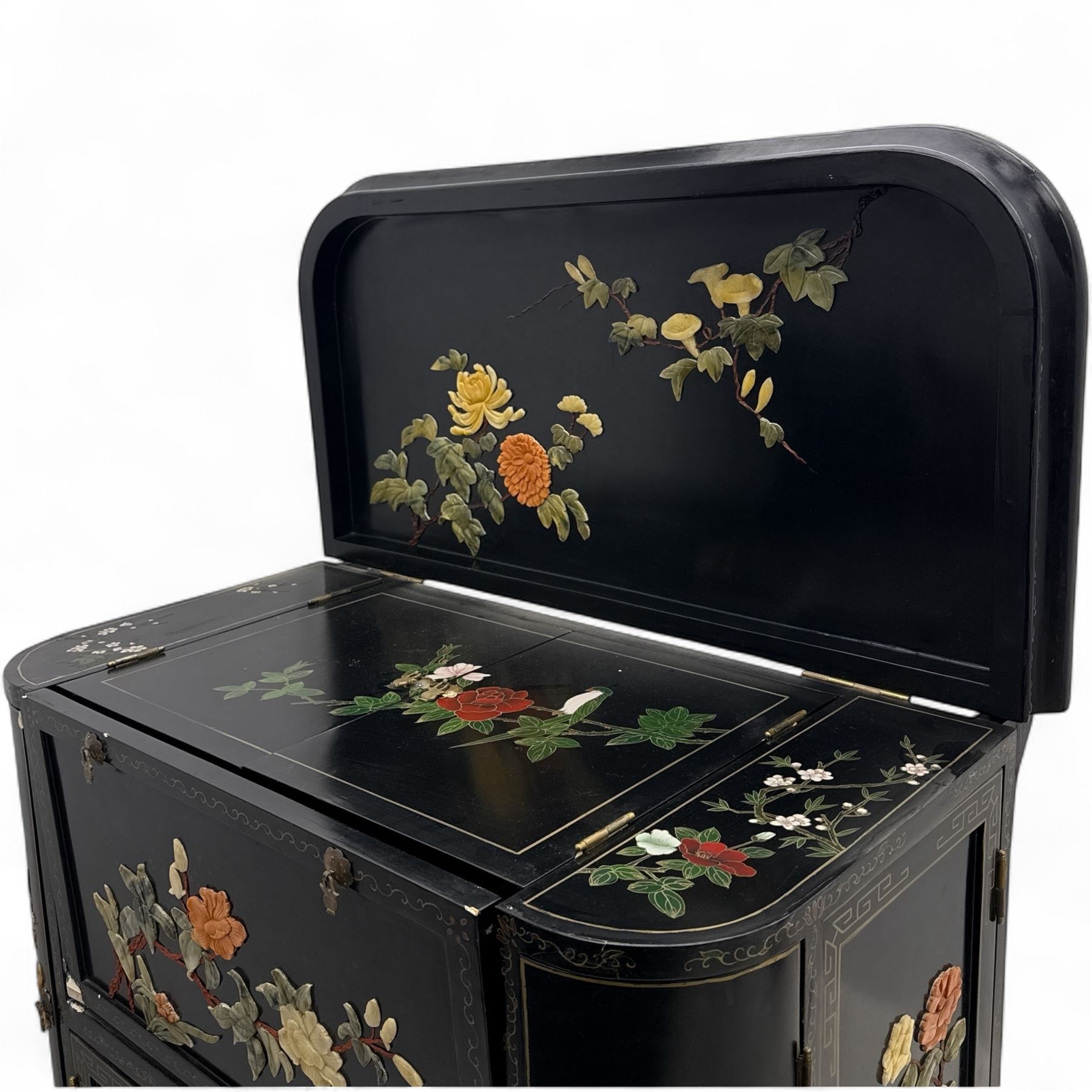 Early 20th century Chinoiserie lacquered cabinet, rounded rectangular top above a fall front enclosing fitted interior with lacquered decoration, over a pair of cupboard doors and flanked by side compartments with tiered bottle shelves, the black lacquer ground decorated throughout with raised and painted floral sprays, on shaped bracket feet