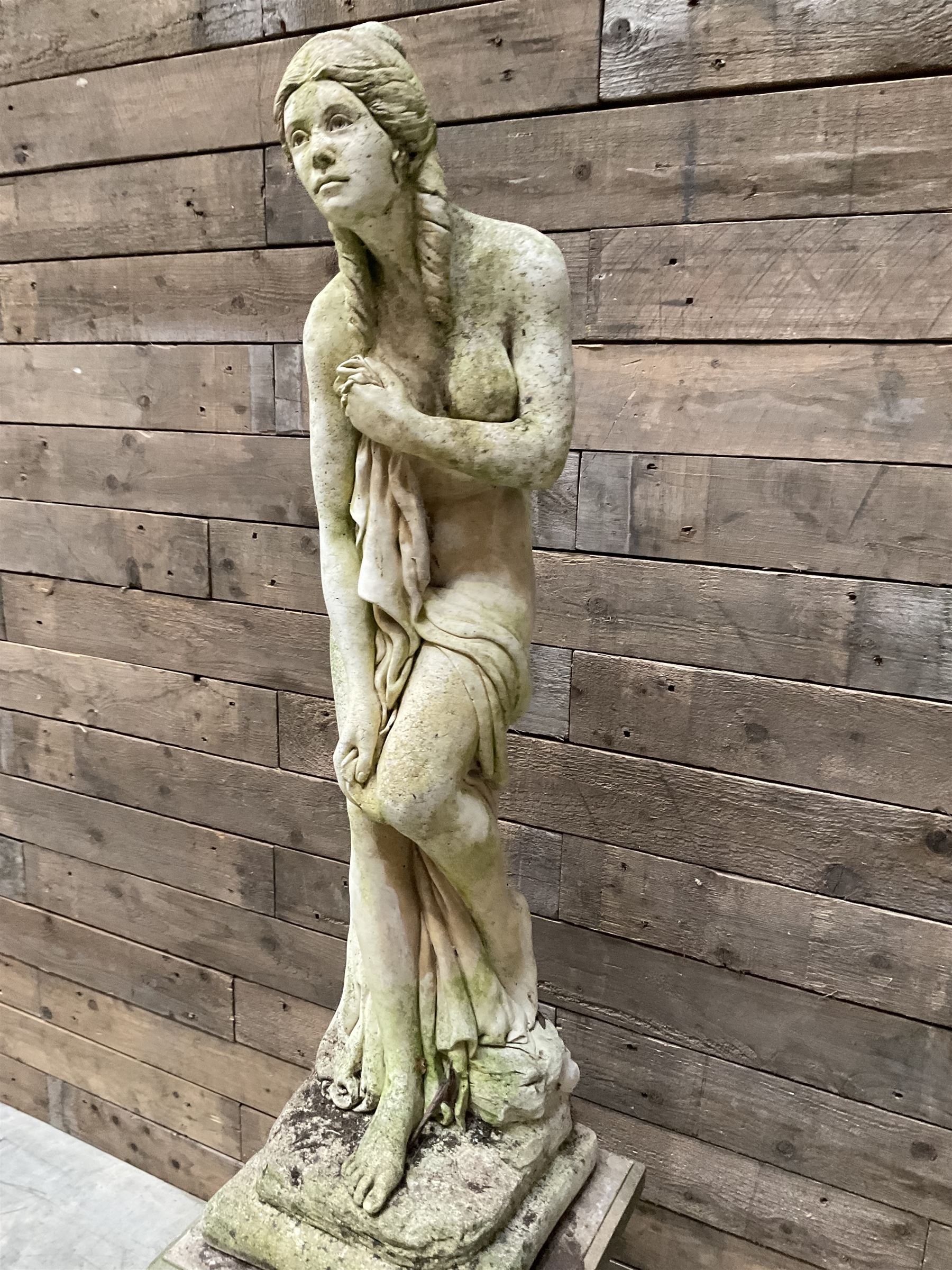 Cast stone garden figure of a bathing lady, raised on square plinth