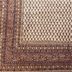 West Persian Botteh-Mir hand-knotted rug, ivory field decorated with an overall dense lattice design of small repeating boteh motifs in muted blue, rust, and brown tones, enclosed by a series of narrow borders incorporating stylized geometric and floral patterns with cotton fringe ends 