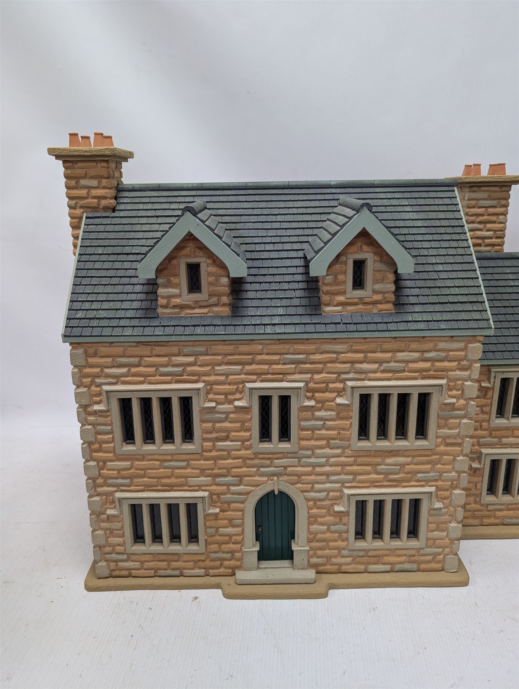 1:24 scale stone effect three-storey cottage dolls house, with green arched door and lattice effect windows, decorated to the interior with wooden floors, wired lighting and fire places, H45cm, W57cm, D26cm