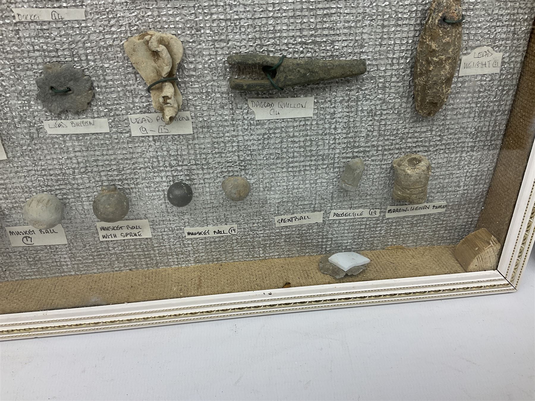Collection of metal detecting finds, most contained within display frames and labelled, some loose, to include musket balls, bill hook, axe fragment, hubcaps, shell cases, regimental badges, coins, etc. 