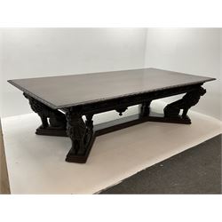 Large 19th century carved oak library table, the rectangular top with lunette carved edge over cartouche panelled and carved  scroll frieze, the central tapering rectangular support relief carved with masks and garlands, on four carved seated lion supports at each corner, on flat angular stretcher with recessed castors stamped ‘Bartholomew & Fletcher, London’