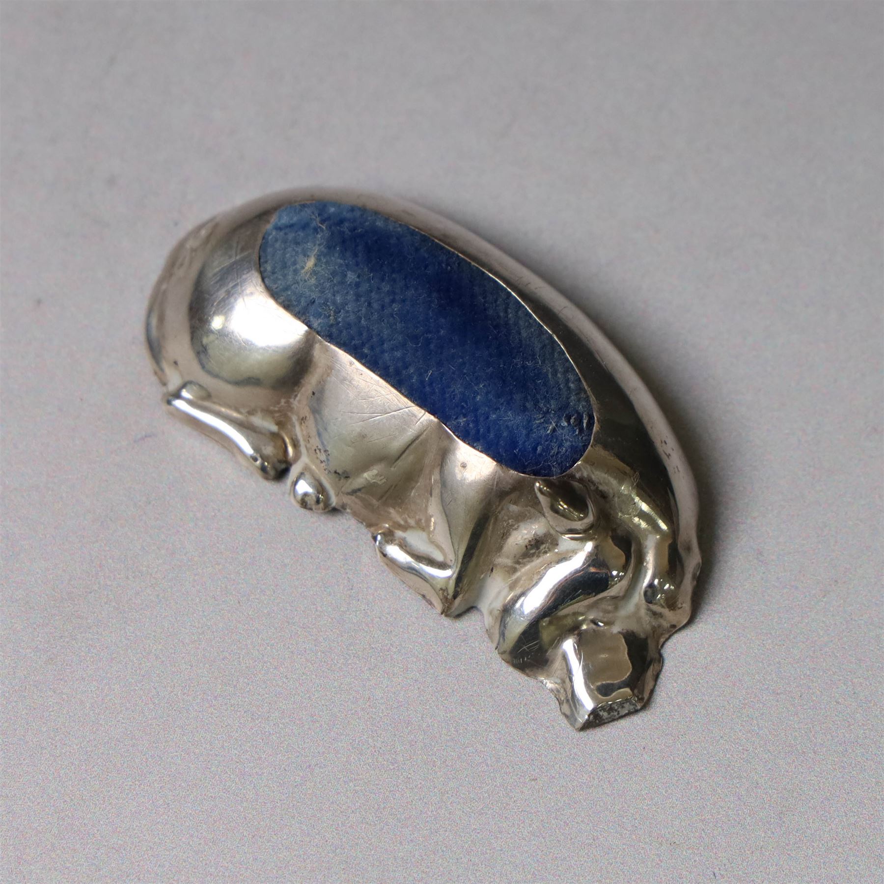 Early 20th century silver novelty pin cushion, modelled as a recumbent pig with blue cushioned back, hallmarked Williams (Birmingham) Ltd, Birmingham 1910, W5.5cm