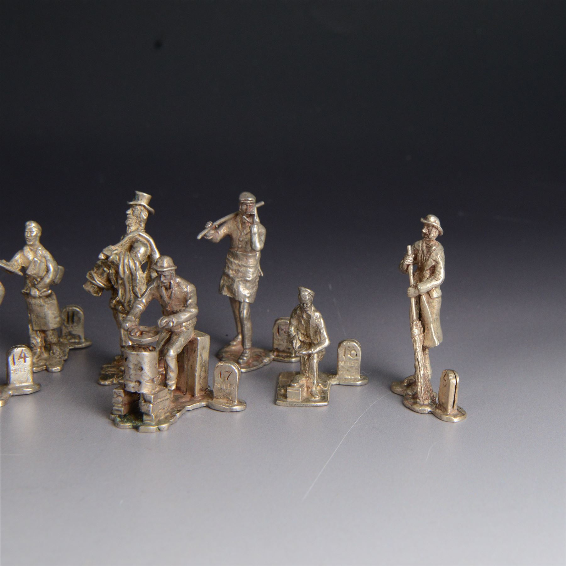 Set of twelve silver place card holders from the 'Cries of London' series, each depicting traditional London street traders, hallmarked Thomas Charles Jarvis, London 1975, tallest H6.5cm
