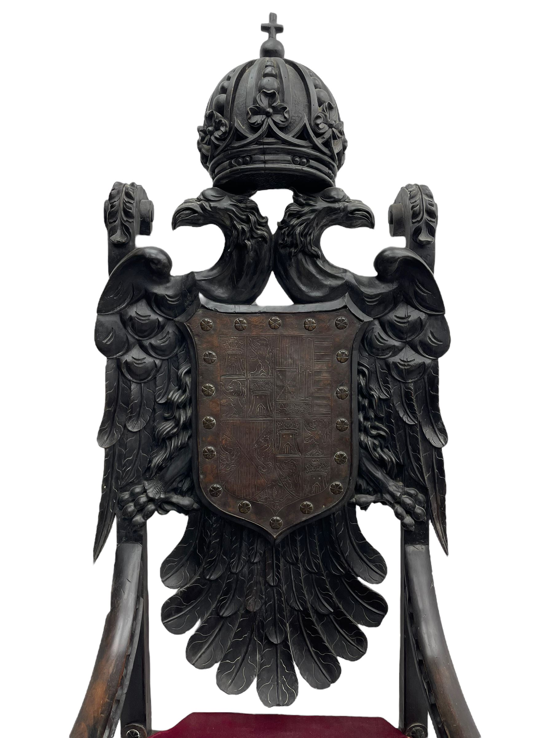 Grand mid-to-late 19th century heavily carved beech framed throne chair, the crown pediment carved with flower heads and cross finial, scroll and acanthus carved upright supports with twin perching griffin back enclosing etched leather work heraldic shield with castle and lion motifs over splayed feathers, flower head carved down sweeping arms with grotesque carved terminals, the seat rails carved with further flower heads on moulded supports with oversized ball and claw carved feet

Provenance: A very similar chair was used in the filming of Stanley Kubrick's 'Eyes Wide Shut' (1999)
