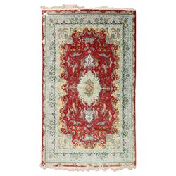 Persian silk inlaid crimson ground Kashan rug, the central shaped field with a floral pole...