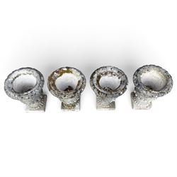 Set of four weathered composite stone urns of campana form, the everted leaf-moulded rolled rim over a body decorated with scrolling fruiting grapevines in relief, over a gadrooned underbelly and waisted socle, lobed collar on square base