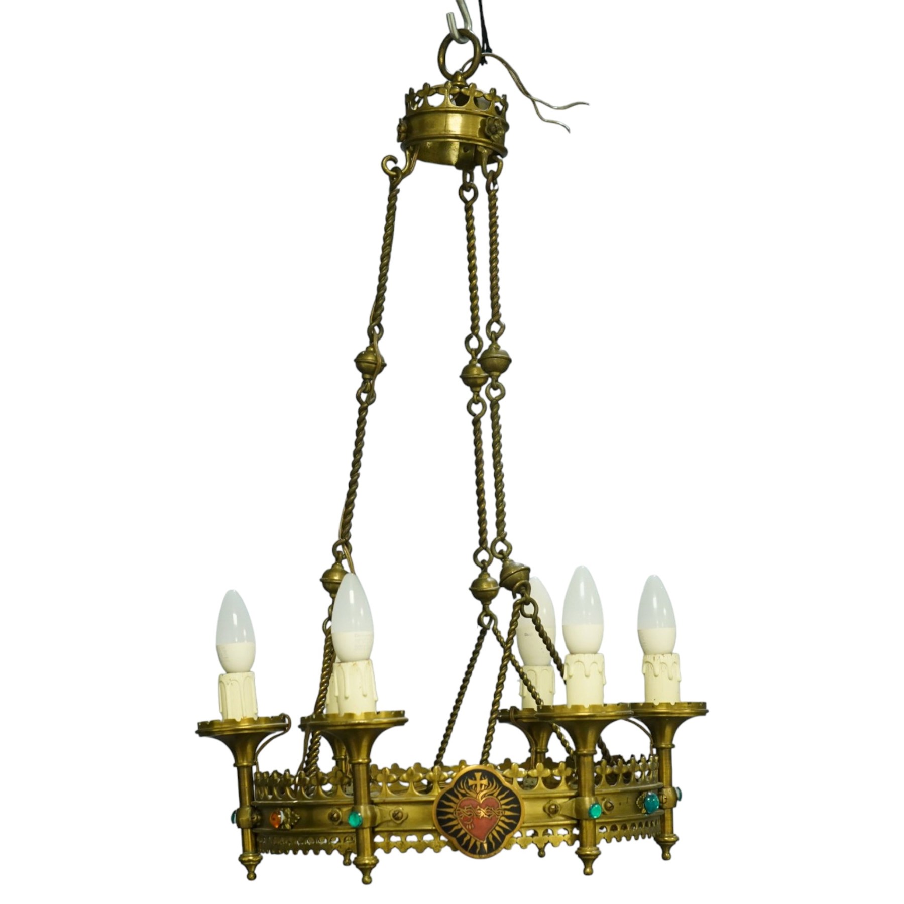 Gothic Revival brass six-light ecclesiastical chandelier, circular frame with pierced trefoil cresting and apron, applied with polychrome Sacred Heart medallions, six candle-form electric sconces, suspended on twisted brass rods and chains from a coronet-form ceiling boss