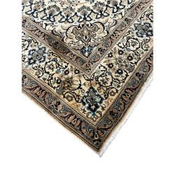 Persian Kashan ivory ground carpet, central rosette medallion surrounded by swirling leafy branches and floral sprays, the main border with scrolling pattern interspersed with floral motifs, within guard stripes 