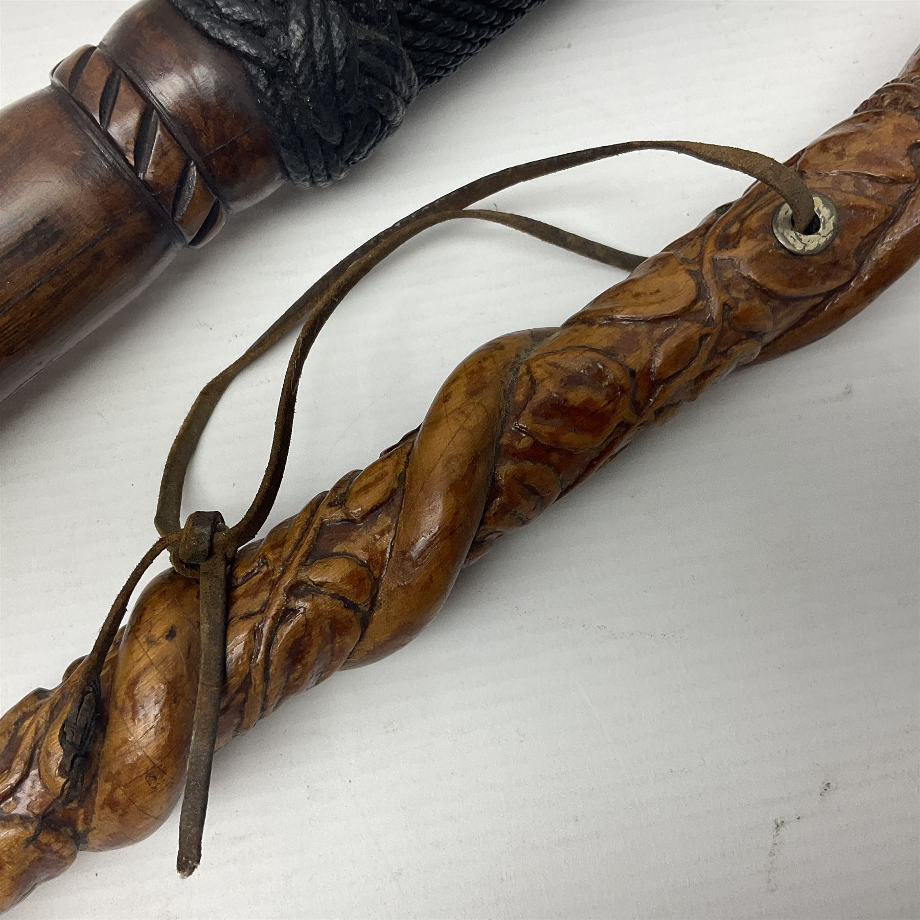 19th century wooden walking stick, the handle carved as a snake within a clenched fist, the cane carved with foliate and cross hatched decoration, with a metal spike to base, together with a turned wooden walking stick, with lacquered rope nautical knot handle, tallest L96.5cm
