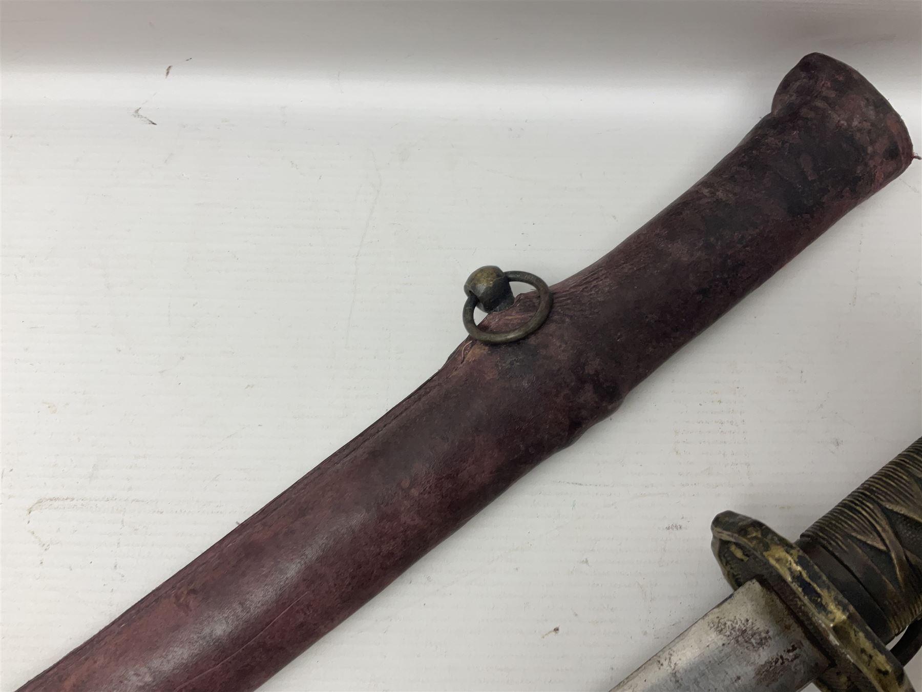 Copy of a WWII Japanese NCO sword, the 65cm slightly curving blade stamped with pseudo Japanese characters and cast brass simulated cord bound grip; in officer's leather bound field scabbard L97cm overall