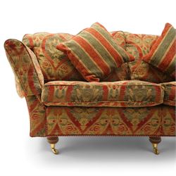 Duresta - traditional shape two-seat sofa with out-swept arms, upholstered in crimson ground fabric decorated with palmettes and foliate motifs with matching loose and scatter cushions, raised on compressed bun feet with brass cups and castors
