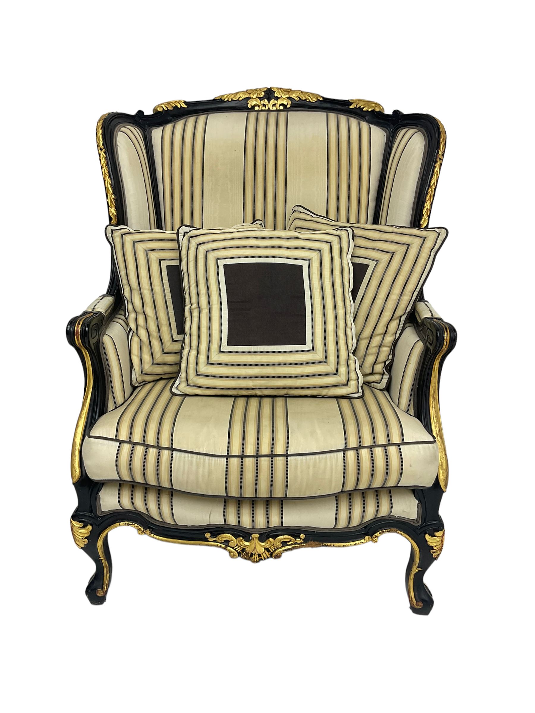 Thomas Messel - Georgian style ebonised and gilt wingback armchair, upholstered in striped fabric, on cabriole front feet