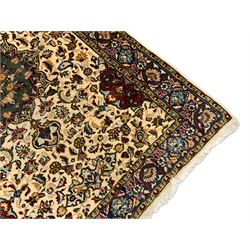 Persian ivory ground rug, central green floral pole medallion within a field decorated by scrolling foliate patterns, the guarded border with repeating palmettes and floral designs
