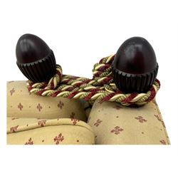 20th century Knole design two seat sofa, high back and double drop-arm joined by mahogany finials and ties, upholstered in camel ground fabric with red lozenge design, on turned supports with brass castors