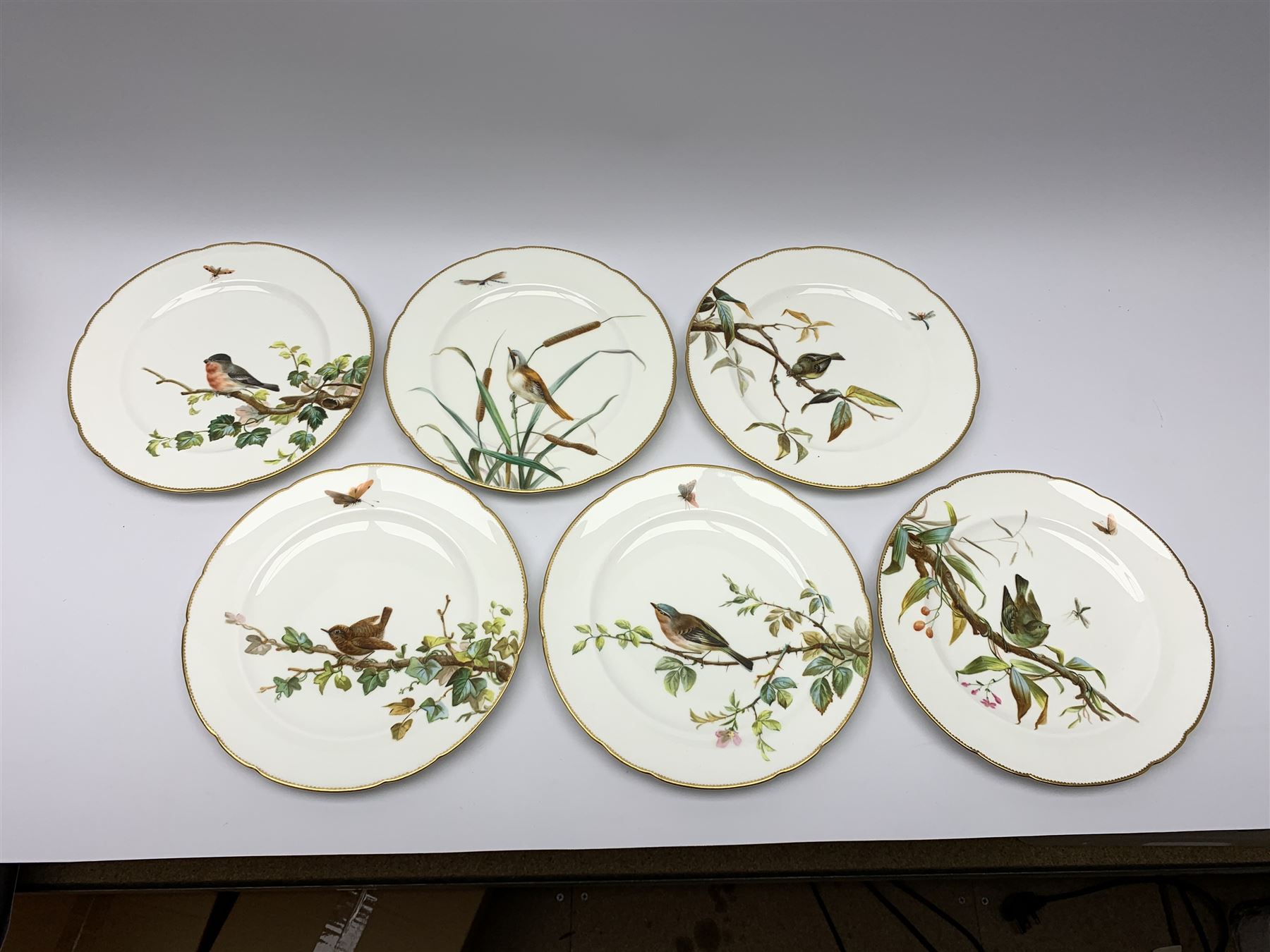 19th century Minton dessert service, comprising four comports, one tazza, and twelve plates, each hand painted with birds perched upon branches, and further detailed with insects and heightened in gilt, with printed retailers mark beneath for John Mortlock Oxford Street London, and impressed Minton mark to most, comport H13.5cm, plates D23.5cm. 
