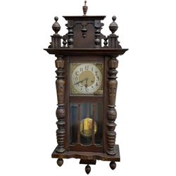 German wall clock in a mahogany vase with turned columns and finials, eight day spring driven movement striking the hours on a gong, brass dial with a silvered chapter ring, Arabic numerals and steel spade hands.