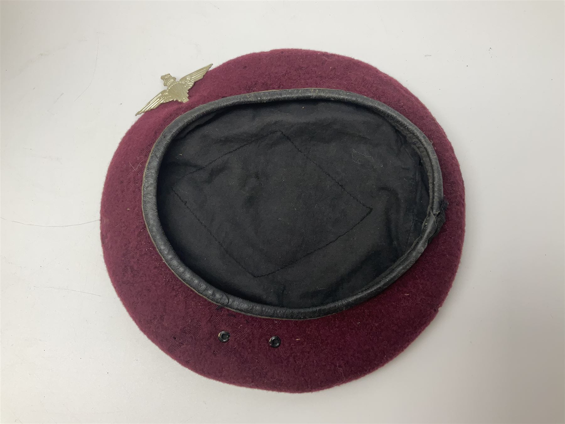 WW2 British Airborne Troops/Paratroopers Steel Helmet with green textured paint finish and netting cover, leather and sponge liner and three point chinstrap mounting; liner marked BMB 1943; together with a paratrooper's maroon beret with metal badge (2)