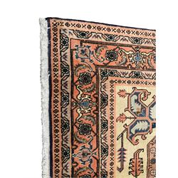 Persian ivory and peach ground, overall geometric design, the field with central star medallion surround stylised leaf motifs, guarded geometric design border