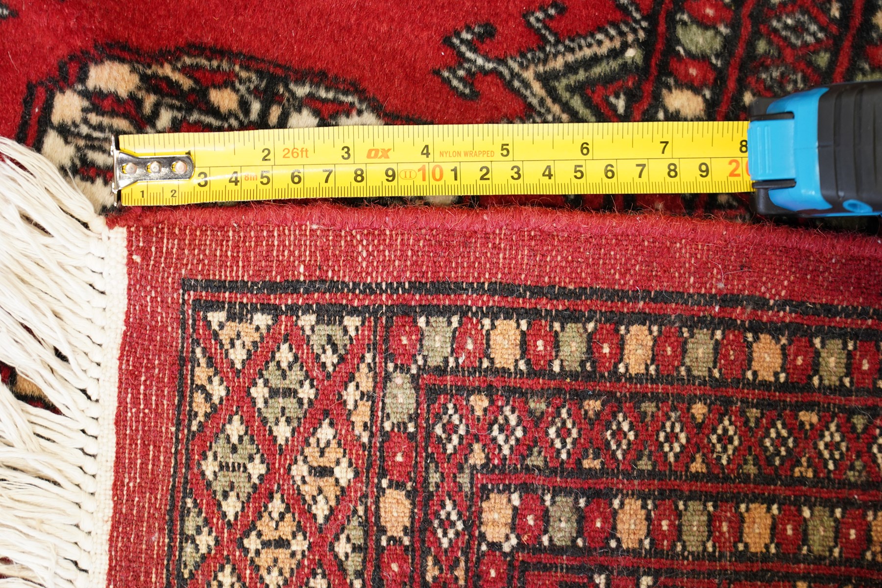 Two Afghan Bokhara crimson ground rugs, the fields decorated with repeating Gul motifs with geometric guard bands (126x190 & 157x250)