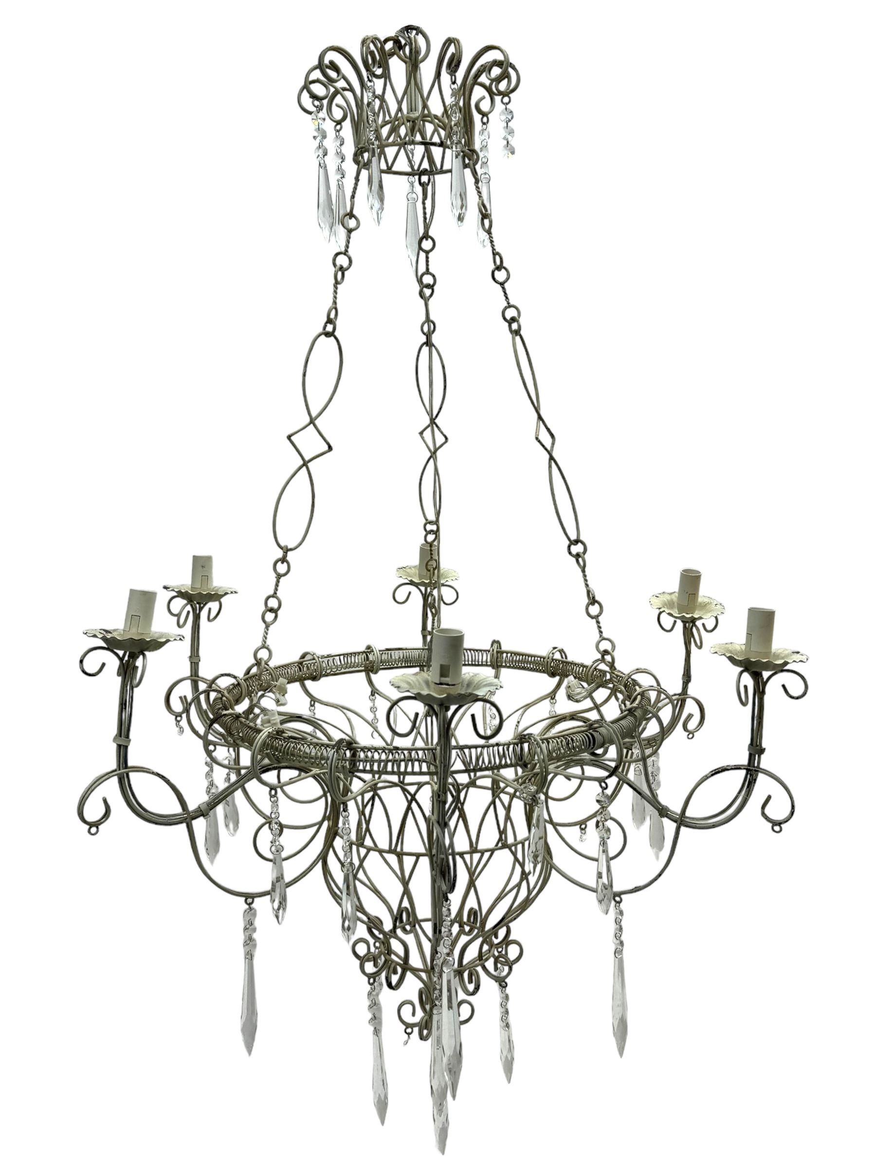 India Jane Interiors - six branch metal chandelier, the scrolled crown over circular bulbous body with six projecting branches, decorated with scroll work and glass pendants, in distressed white paint finish - ex-display/bankruptcy stock 