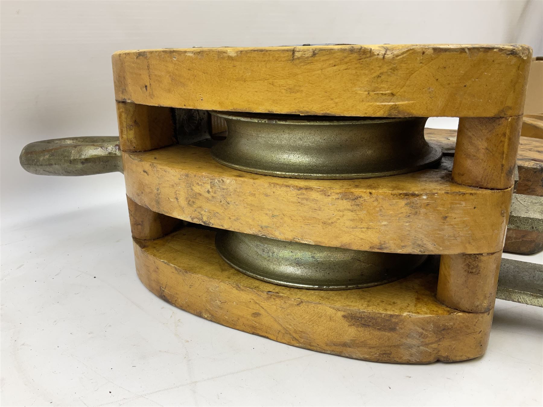 Three ship pulleys comprising wooden block double with swivel eye marked 'wooden block 240mm double rope: 22mm',  wooden block double with upset shackle and wooden block with stiff swivel hook, largest example L50cm